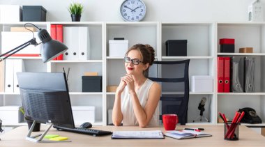 Genç bir kız ofiste masada oturuyor.