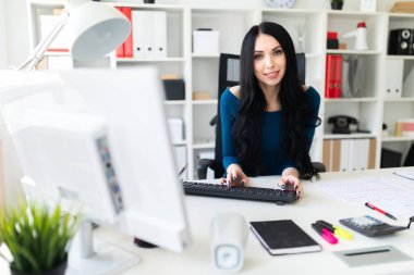 Genç bir kız ofis masada oturan ve metin klavyede yazarak.