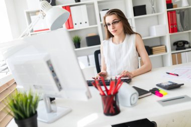 Güzel genç kız masa ofis ve yazarak metin klavyede oturur.