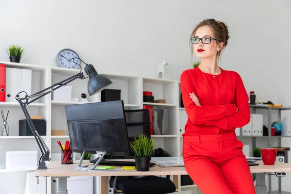 Uma jovem está de pé apoiada em uma mesa no escritório. — Fotografia de Stock