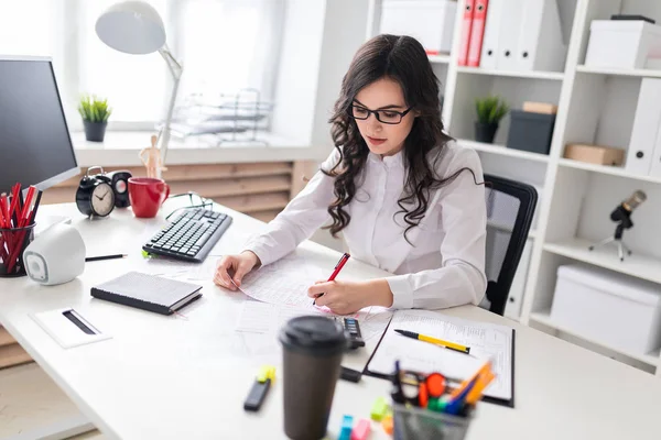 Young girl sits at office desk and fills documents with her left hand. — Stock Photo, Image