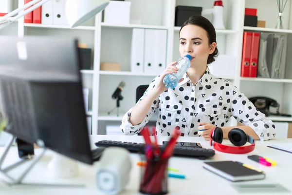 Beyaz bir bluz geometrik desen ve mavi kot pantolon güzel genç kız. Siyah saçlı ve güzel makyaj kız. Çekici bir genç kız parlak bir ofiste çalışıyor. alan derinliği ile fotoğraf.
