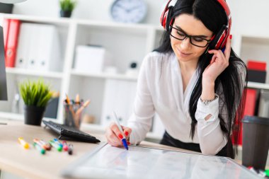 Genç bir kız kulaklık tablo anlamına gelir ve bir işaretleyici manyetik bir tahtaya çizer.