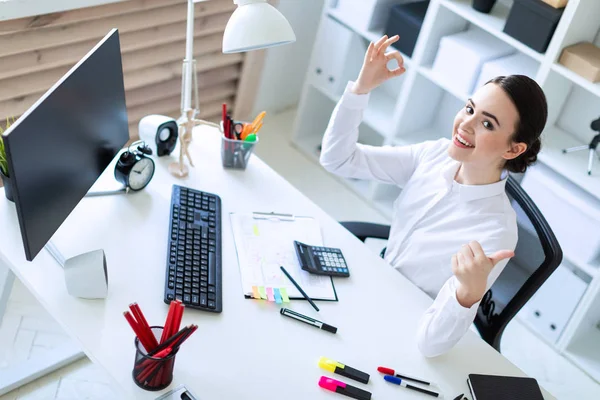 Ofiste genç bir kız bir masada oturuyor, belgeleriyle çalışır ve Tamam ve sınıf bir işareti gösterir.