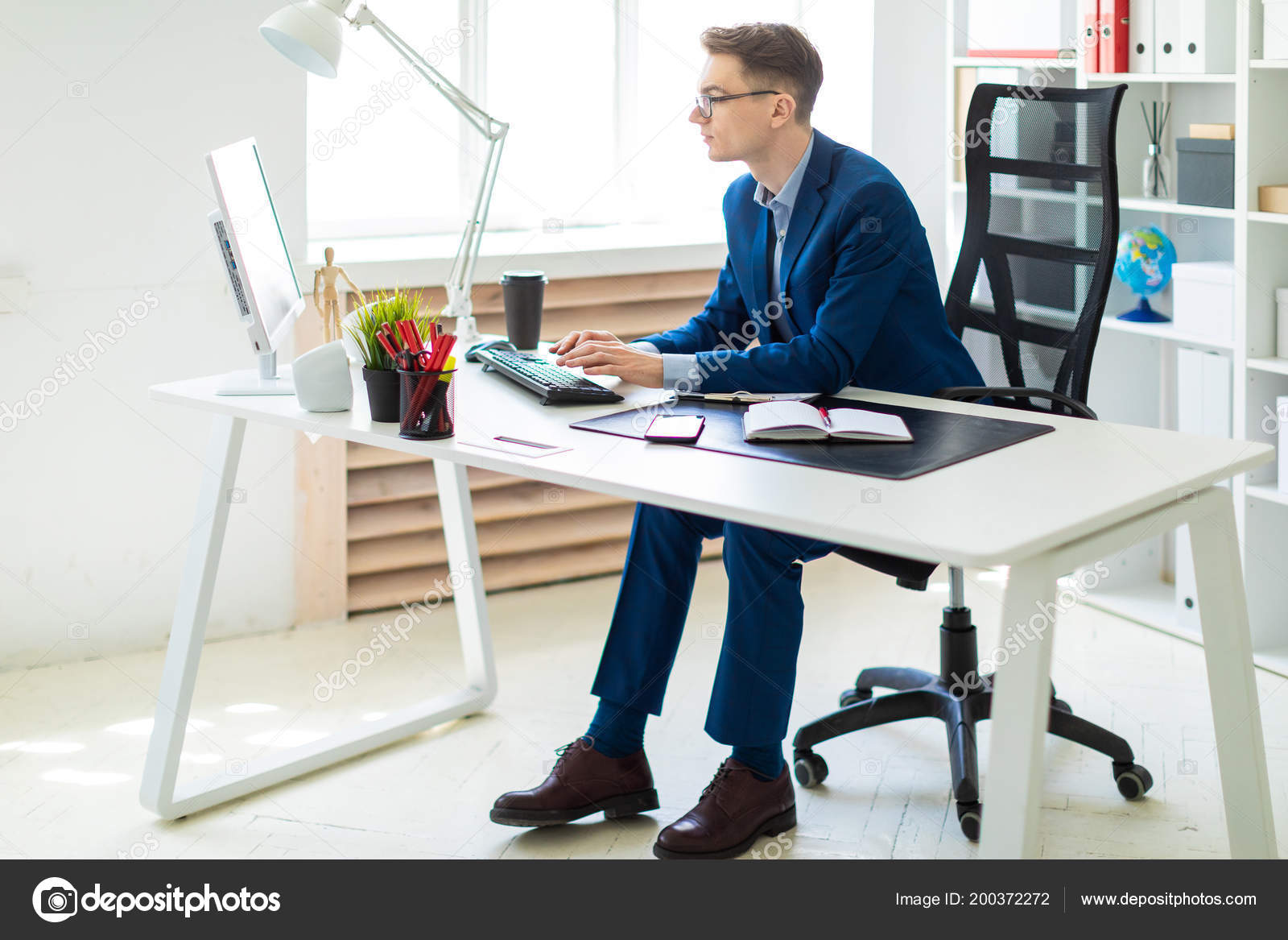 Young man sitting at desk in office and working on computer. Stock