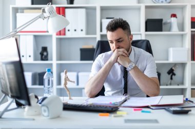 Bir adam ofiste bir masada oturuyor ve ahşap bir küçük adam arıyor.