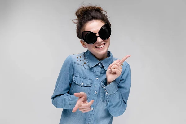 Chica morena joven en gafas negras. Gafas de gato. El pelo está recogido en un moño. Chica bailando . —  Fotos de Stock