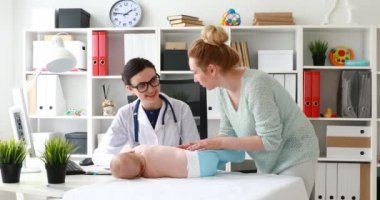 Masanın üzerinde yatan Doktor muayene bebek ile anne