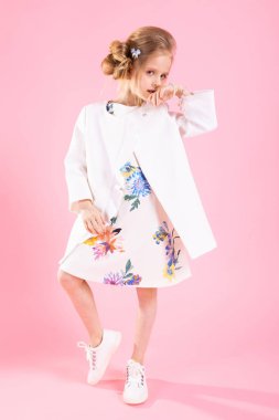 Pembe bir arka plan üzerinde poz ışık giysili bir genç kız.