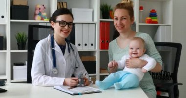 Beyaz Oda, çocuk doktoru resepsiyonda kameraya gülümseyen çocuk ile anne