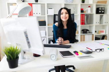 Genç bir kız masada ofisinde oturuyor.