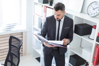 Ofis ve belgeler klasörüyle ile verilirse rafa yakın duran adam.