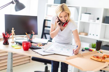 Genç bir kız bir masanın ayakta, telefonda konuşurken ve bir işaretleyici elinde tutan. Masaya manyetik bir pansiyondur. Kızlar kulaklık boynuna asmak.