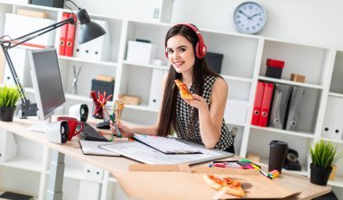 Genç bir kız bir tablo bir yeşil işareti ve bir parça pizza elinde tutan duruyor. Önce kız masanın üzerinde manyetik bir pansiyondur. Kulaklıklar giyen kız kafasına.