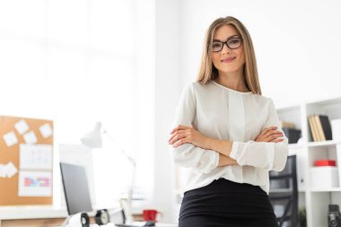 Genç bir kız ofiste bir masaya yaslanmış duruyor..