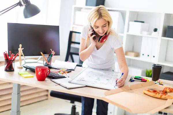 Genç bir kız bir masanın ayakta, telefonda konuşurken ve bir işaretleyici elinde tutan. Masaya manyetik bir pansiyondur. Kızlar kulaklık boynuna asmak.