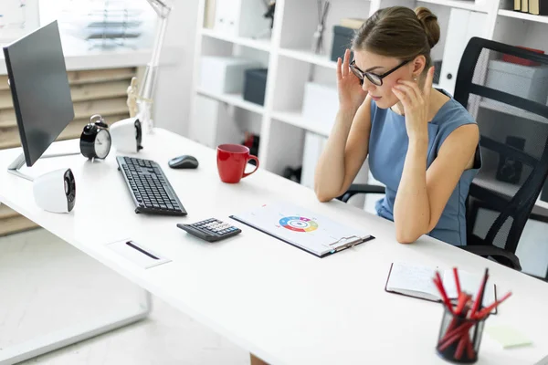 Genç bir kız ofiste bir masada oturur ve bir belgeyi içeren bir grafik görünüyor.