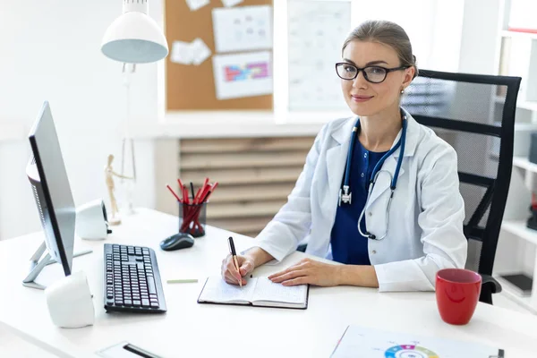 Beyaz bir elbise içinde genç bir kız ofiste masalarda oturur ve bir kalem elinde tutar. Bir stetoskop boynunda asılı.