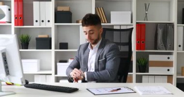 beyaz ofis masada oturan, saat bakarak ve ofis-koltuğu bırakarak işadamı takım elbise ceket 
