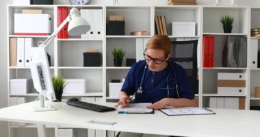 İşyerinde oturan ve belgeleri işaretleme mavi önlük doktor