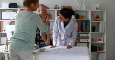 Anne ve genç doktor muayene çocuk masasında