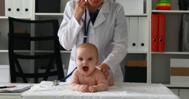 Masaya yeni doğan bebekle yordamları gerçekleştirirken çocuk doktoru
