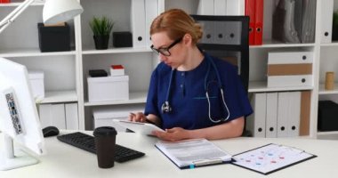 İşyerinde oturan ve tablet üzerinde çalışan doktor