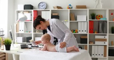 bebekle oynarken ve başparmak kameraya gösteren genç doktor 