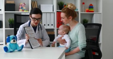 Doktor tanı için dinleme elinde bebekle anne