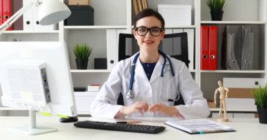 gülümseyen ve jestleri Tamam gösterilen masada oturan doktor 