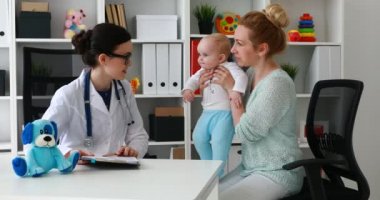 Resepsiyonda bir genç kadın doktor çocuk ile anne