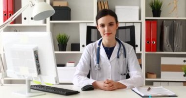 El çene ve kameraya bakarak yükselterek işyerinde oturan doktor