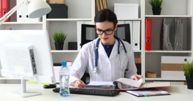 Doktor masada oturan ve belgeler klasörüyle kaydırma gözlük