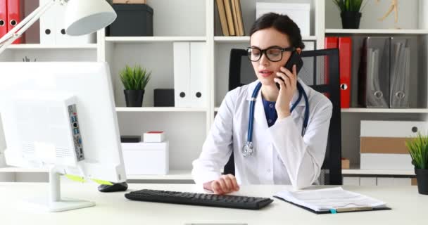 Läkare Pratar Telefon Och Tittar Bildskärm — Stockvideo