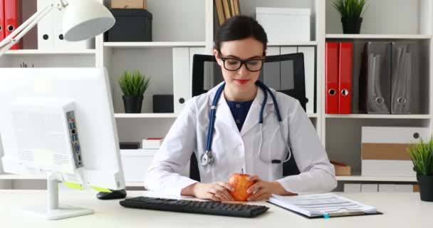 Lekarz Siedzi Przy Stole Patrząc Czerwone Jabłko Tworzących Kciuka — Wideo stockowe