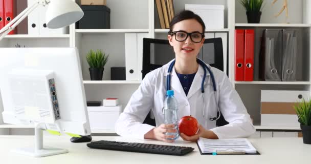 女医生拿瓶水和苹果在手和提供他们 — 图库视频影像