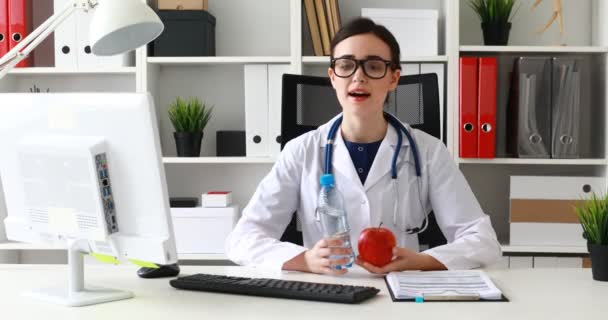 Doctor Sitting White Table Holding Red Apple Bottle Water Offering — Stock Video