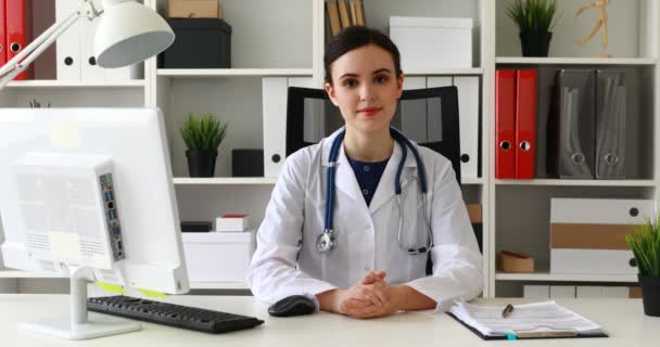 Dokter Zitten Werkplek Verhogen Van Hand Aan Kin Camera Kijken — Stockvideo