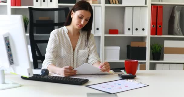 Geschäftsfrau Sitzt Arbeitsplatz Und Liest Und Blickt Die Kamera — Stockvideo