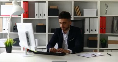 Genç işadamı ofiste bilgisayarla çalışıyor. 