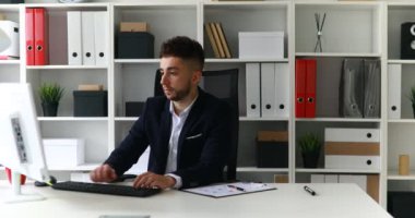 Genç işadamı ofiste bilgisayarla çalışıyor.