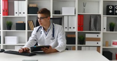 Genç doktor bilgisayarda belgeleriyle çalışma