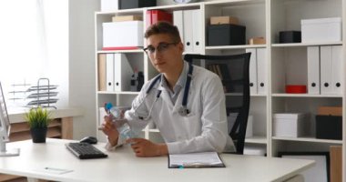 Doktor su şişe masanın üstüne koy. 