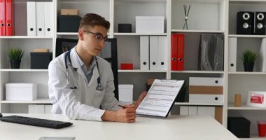 Kağıt gösterilen ve kameraya bakarak genç doktor