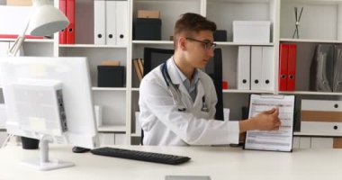 Kağıt gösterilen ve kameraya bakarak genç doktor