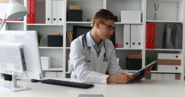 Kağıt gösterilen ve kameraya gülümseyen genç doktor