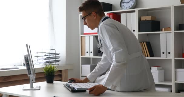 年轻医生在工作场所的计算机文件 — 图库视频影像