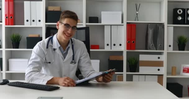 Joven Médico Investigando Documentos Sonriendo Cámara — Vídeo de stock