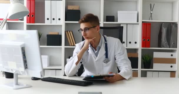 Joven Médico Trabajando Con Documentos Computadora — Vídeo de stock