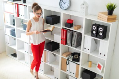 Genç bir kız raf standları ve açık bir kitap onun elinde tutan.